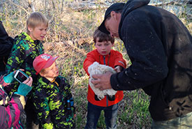 Bruce Boldt teaching kids from the Saskatoon Nature Society how to handle a recently banded baby great horned owl (not a short-eared) on his farm's property this spring. (Photo by Matthew Braun/NCC staff)