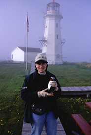 Me holding an Atlantic puffin in front of a lighthouse. (Photo courtesy of Laurel Bernard)