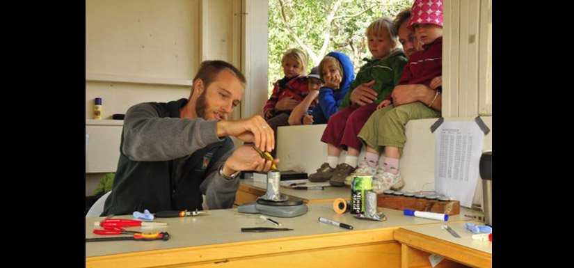 Chris Chutter shows some visitors how to weight the small songbirds. (Photo by Steve Ogle)