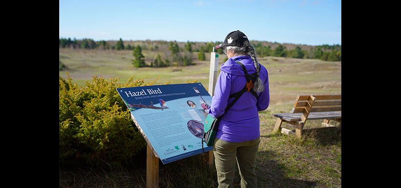 Two women with a passion for conservation — Jennifer Jackman reading about Hazel Bird at Hazel Bird Nature Reserve, ON (Photo by Chelsea Marcantonio/NCC staff)