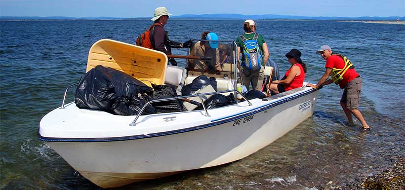 Volunteers gather garbage on a boat as they clean up the shores at Sandy Point (Photo by A. Mahoney)